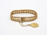 Gros plan sur un bracelet en or orné d'une pièce de monnaie