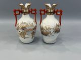 deux vases blancs avec des anses rouges posés sur une surface grise
