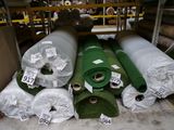 Plusieurs rouleaux de gazon synthétique sont empilés les uns sur les autres dans un entrepôt