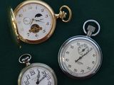 three different types of pocket watches on a green surface