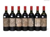 six bottles of wine are lined up in a row on a white surface