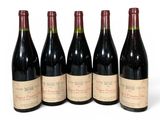 six bouteilles de vin sont alignées sur une surface blanche