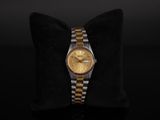 a gold and silver watch sitting on top of a black pillow