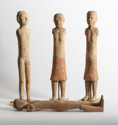three figurines of three people standing on a piece of wood