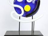 a blue and white sculpture on a black stand with a yellow dot