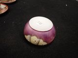 a purple bowl sitting on a black table with plates of food in the background