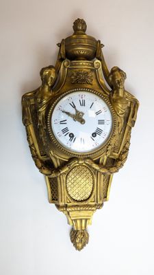 une horloge dorée accrochée au mur, avec des chiffres romains