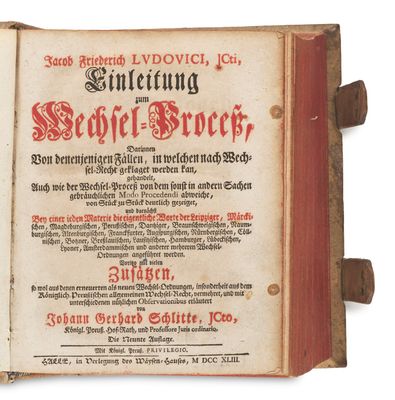 an old book with a red cover sitting on top of a table