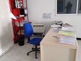 un bureau avec une chaise et une étagère dans le coin