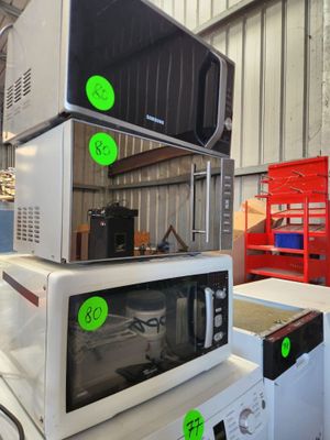 trois micro-ondes empilés les uns sur les autres dans un entrepôt