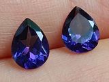 une paire de pierres précieuses bleues et violettes au doigt d'une personne