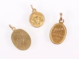 three gold coin pendants on a white surface with a white background