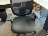 a black office chair sitting in front of a computer desk