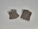 une paire de porte-monnaie en métal argenté posés sur une surface blanche
