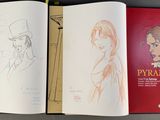 three books that are open on a table