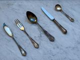 Plusieurs cuillères, fourchettes et couteaux sont alignés sur une table