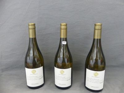 three bottles of white wine are lined up on a table