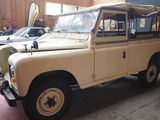 a tan land rover parked in a garage next to other cars