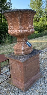 a stone urn sitting on a pedestal next to a chair