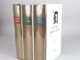 three books are stacked on top of each other on a white surface