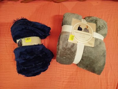 deux couvertures posées sur un lit recouvert de draps orange