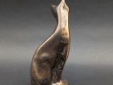 a bronze statue of a cat sitting on a black surface