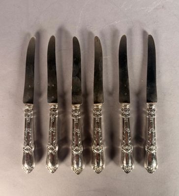 six silverplated knives are lined up in a row on a white surface