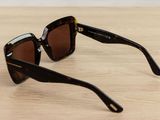 sunglasses on a wooden table with a white wall in the background