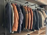 a lot of jackets hanging on a rack in a room