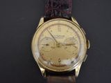 a gold watch with a brown leather strap on a black surface