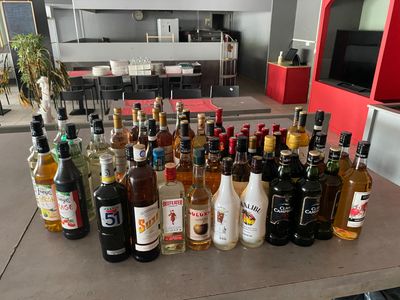 Des bouteilles d'alcool sont alignées sur une table devant un téléviseur