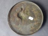 a metal plate with a bird on it sitting on a table