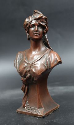 an antique bronze bust of a woman with a bird on her shoulder