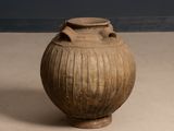a large vase sitting on a table with a blue wall in the background
