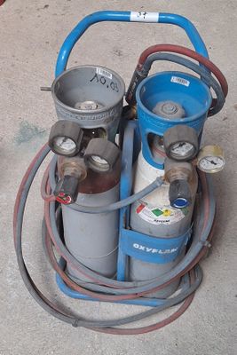 two propane gas cylinders and a hose on the ground