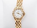 a close up of a gold watch on a white pillow