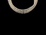 un ensemble composé d'un collier et de boucles d'oreilles en perles blanches sur fond noir