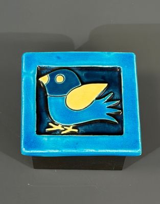 un oiseau bleu et jaune posé sur une assiette bleue