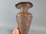 a person holding a metal vase in their hand