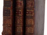 two old books sitting on top of each other on a white surface