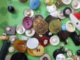 a lot of buttons on a table with a pair of scissors and a pair of scissors