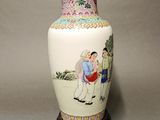a white vase with a painting on it sitting on a table