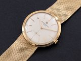 a close up of a gold watch on a black surface