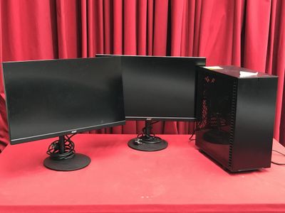 deux écrans d'ordinateur posés sur une table rouge, devant un rideau rouge