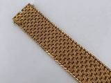 a gold bracelet with a woven design on it