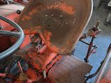 an old red tractor in a garage with a steering wheel