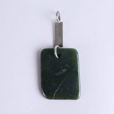 a green stone pendant with a silver clasp on a white surface