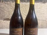 two bottles of wine sitting on a table next to each other