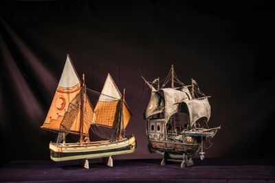 two model ships on display on a purple surface