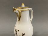 a white and gold coffee pot with a black and white design on it